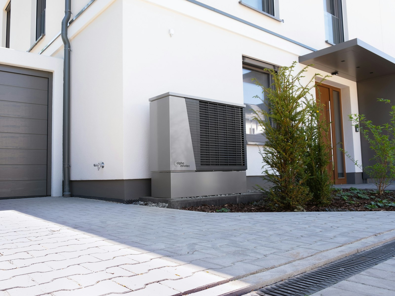 A modern air-source heat pump installed beside the exterior wall of a home.