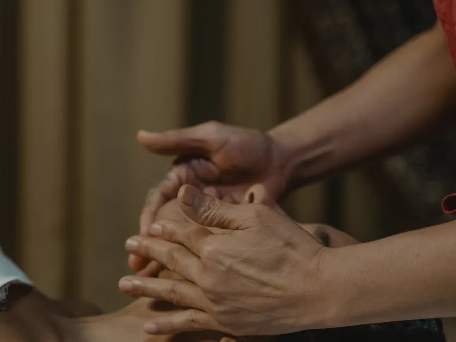 A therapist performing a slow facial massage in warm, low light