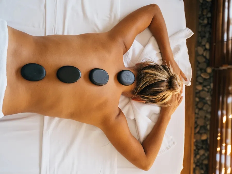 Warm basalt stones resting along a guest’s spine during a hot stone ritual